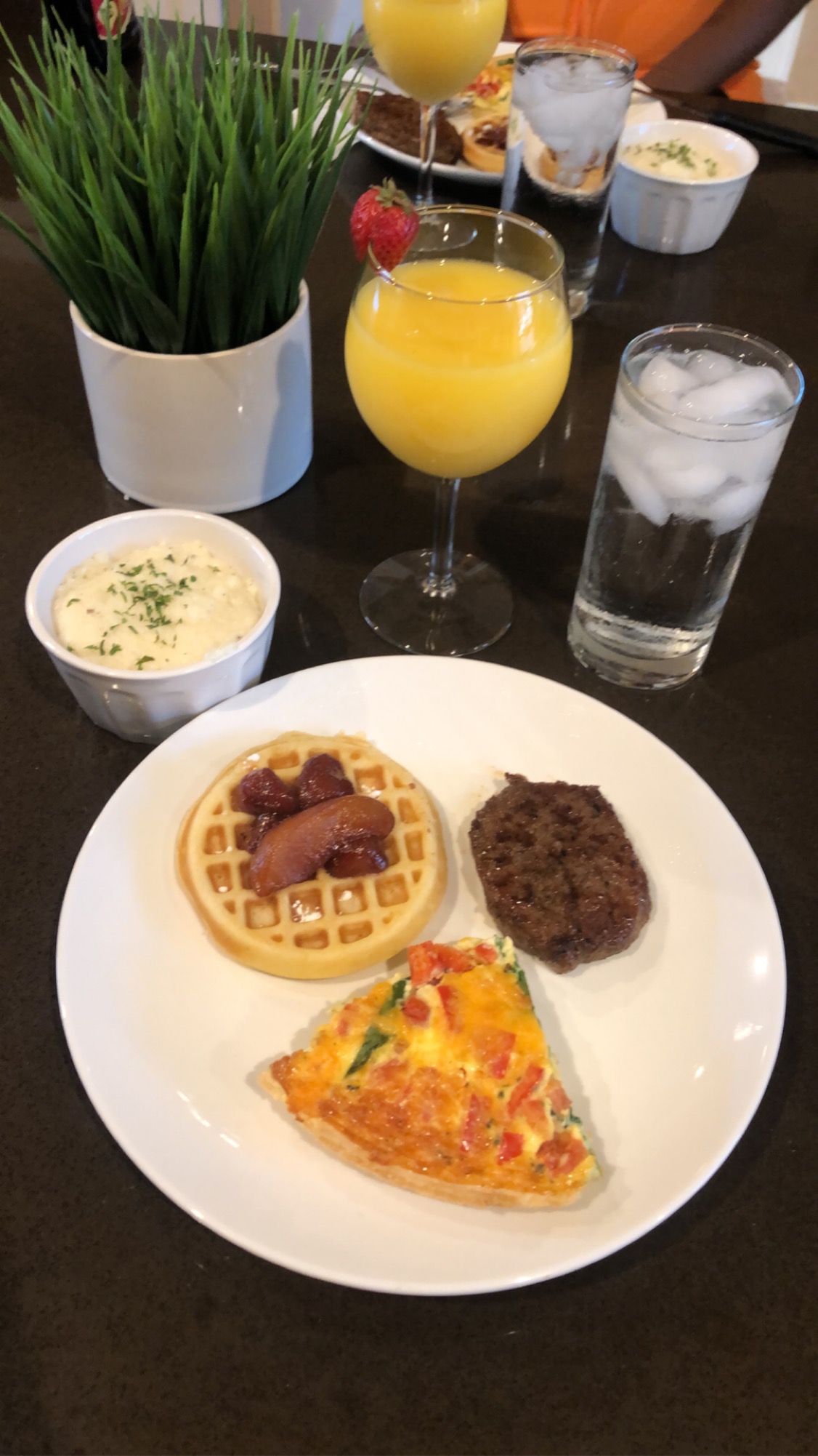 Brunch plate with waffle, sausage, egg dish, and juice
