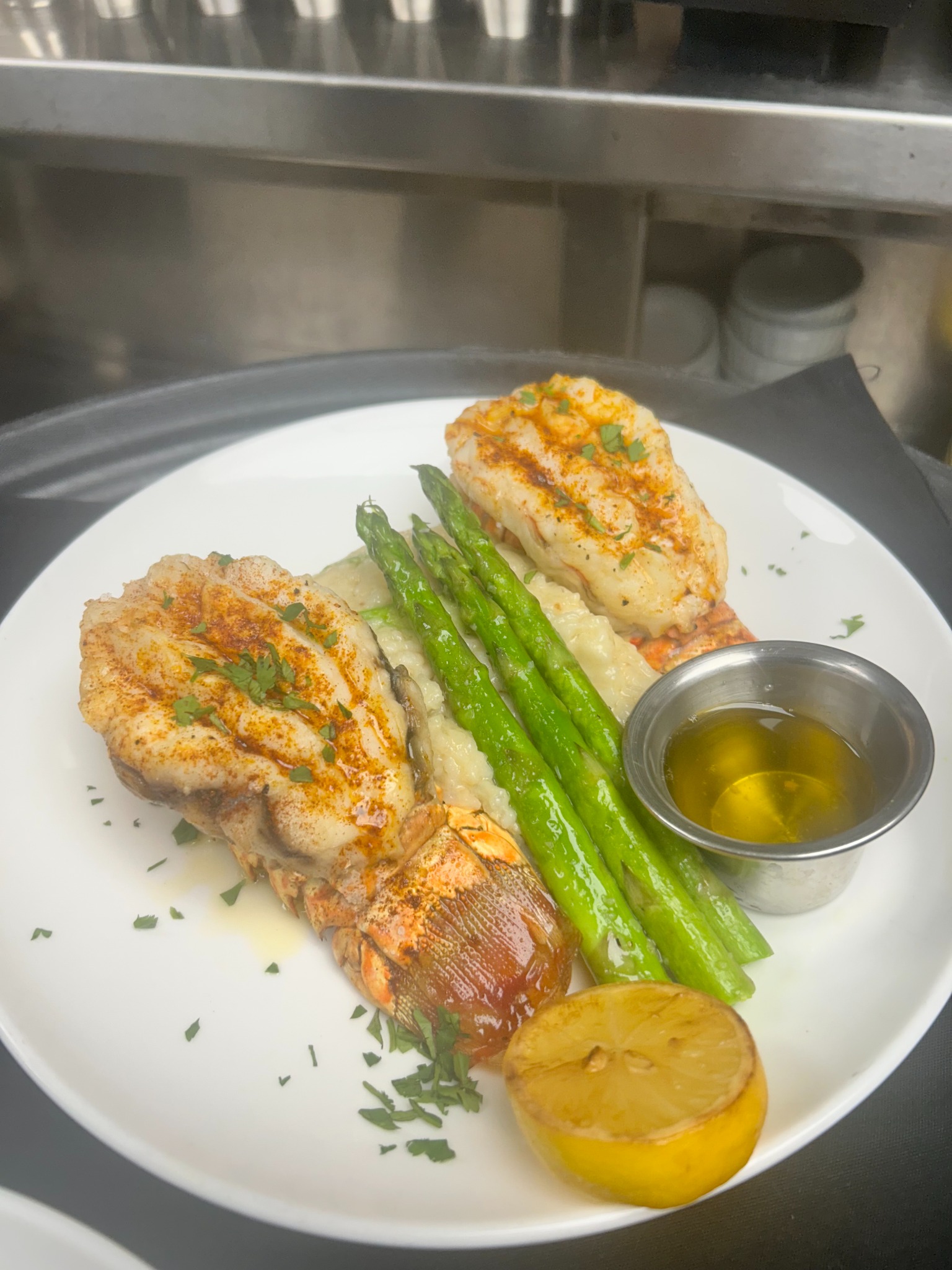 Seasoned lobster tails with creamy risotto, asparagus, and lemon butter