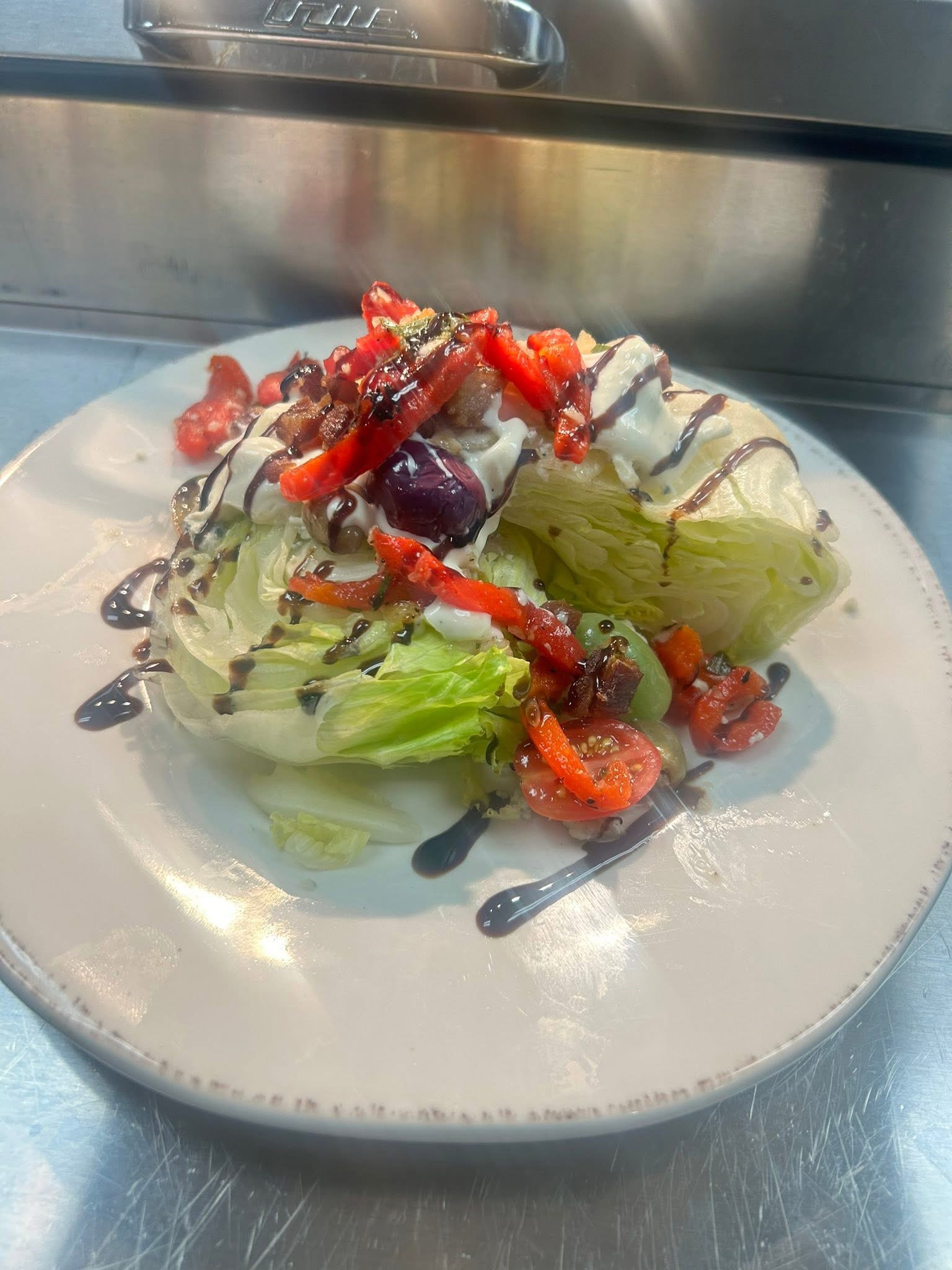 Wedge salad with tomatoes, peppers, bacon, and balsamic drizzle